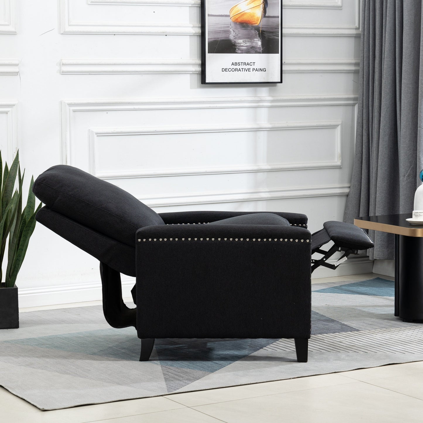 Poltrona reclinabile manuale moderna rivestita in velluto nero con morbidi cuscini e poggiapiedi, decorazione con borchie